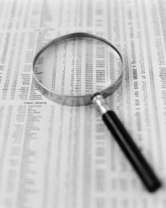 Magnifying glass over financial figures in newspaper